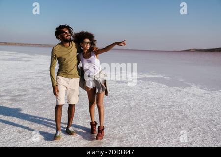 Liebevolles junges afrikanisches Paar, das am Meer entlang geht Stockfoto