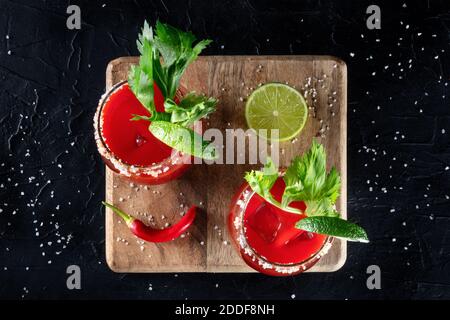 Bloody Mary Cocktail garniert mit Limette und Sellerie, darüber liegende flache Lay Shot mit einem roten Paprika Stockfoto