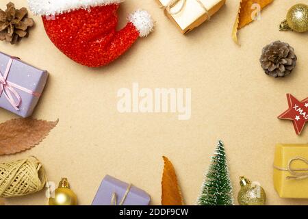 Weihnachtskonzept. Geschenkschachteln mit Tannenbaum, Kugel, Tannenzapfen, weihnachtsmann Hut auf braunem Hintergrund. Flach liegend, Draufsicht, Kopierraum Stockfoto