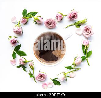 Morgen Tasse Kaffee und schöne Rosenblüten auf weißem Hintergrund, Draufsicht. Gemütliches Frühstück. Flach liegend Stockfoto