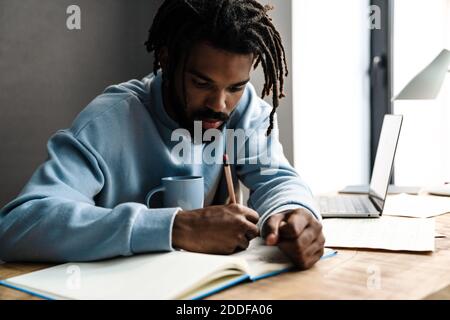 Selbstbewusster junger afrikanischer Freiberufler, der am Schreibtisch arbeitet Stockfoto