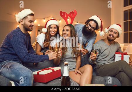 Gruppe von lächelnden Freunden in Urlaub Kappen und Accessoires Schlemmen Weihnachten mit Champagner Stockfoto
