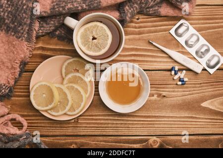 Draufsicht natürliche Heilmittel gegen Grippe Zitrone und Honig mit tasse heißen Tee auf einem Holztisch Thermometer und Pillen Stockfoto