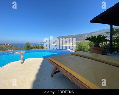 Sommerferienvilla mit schönem Infinity-Pool und tollem Panoramablick auf das Meer in isoliertem privaten Garten. Romantische Urlaubsidee für Paare Sonnendeck. Stockfoto