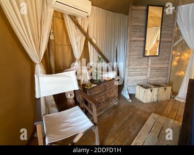 Blaues komfortables Massagebett im beigefarbenen Sommerzelt mit weißen Vorhängen und Meerblick im Freien. Entspannende exotische Luxus Sommerurlaub Therapie im Freien. Stockfoto