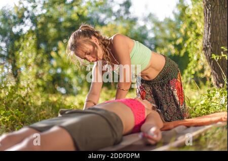 Schönheitsbehandlung. Frau Masseuse bietet eine gründliche Massage im Wald. Stockfoto