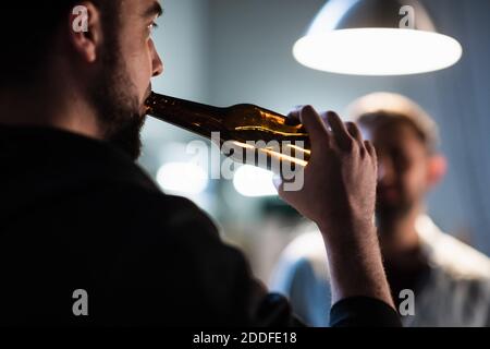 Freunde Jungs versammelten sich bei einem Junggesellenabschied in der Garage, Bier aus dunklen Flaschen trinken auf einer Party Stockfoto