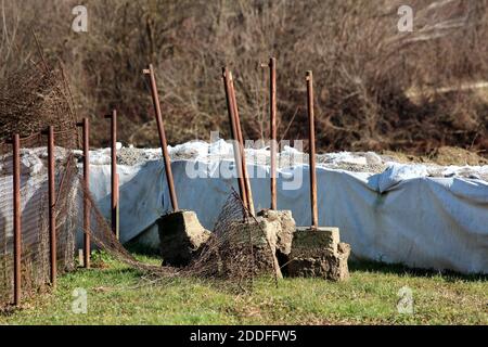 Bündel von komplett verrosteten Metallstangen mit Betonfundament links Von zerstörten Drahtzaun im Familienhaus Hinterhof neben Vorübergehendes Hochwasser Stockfoto