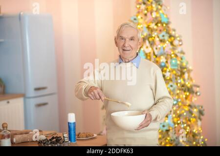 Älterer Mann, der in der Küche kocht und etwas rührt Eine Schüssel Stockfoto