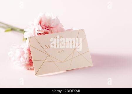 Eine Nahaufnahme einer Muttertagskarte und ein Rosa Blume auf einem rosa Hintergrund Stockfoto