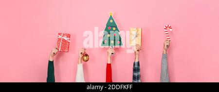 Hände halten Geschenk-Boxen und bunte Weihnachtsdekoration Artikel auf Rosa isolierte Banner Hintergrund Stockfoto