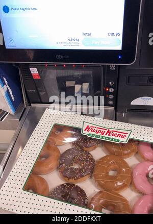 Eine Kiste Krispy Kreme Donuts an der Selbstbedienungskasse in einem Tesco Extra-Geschäft in Wisbech, Cambridgeshire. Cambridgeshire Polizist Simon Read wird vor der Anklage zu versuchen, eine £9.95 Box mit 12 Krispy Kreme Donuts für sieben Pence durch Ankleben eines Barcodes für Karotten auf sie und gehen durch eine Self-Service-Kasse im Tesco Extra-Shop kaufen. Stockfoto