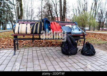 Taschen und Rucksäcke liegen auf einer Parkbank. Stockfoto