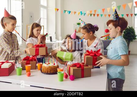 Eine Gruppe von Kindern gibt Geschenke an ihren Freund, der einen Geburtstag mit Freunden feiert. Stockfoto