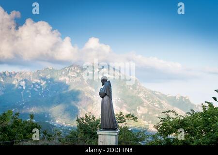 Der Blick über das Tal von der schönen Stadt Ravello an der Amalfiküste, Italien genommen. Die Statue des Paolino Vassallo Memorial sieht auf. Stockfoto