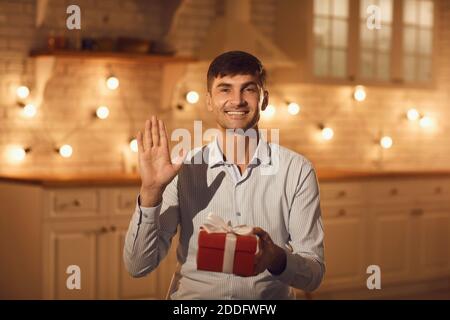 Glücklich Mann halten Geschenk Box und Gruß Freundin online während Online-Meeting Stockfoto