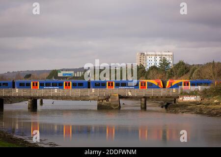 Ein englischer Südwestzug, der über einen Fluss fährt Eine Eisenbahnbrücke Stockfoto