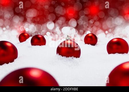 Glänzende rote Weihnachtskugeln im Stock im Schnee mit schönen Rot und mit Bokeh im Hintergrund Stockfoto