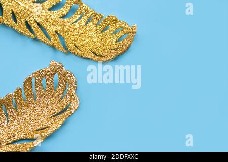 Goldene Ornamente - exotische tropische Blätter auf pastellblauem Hintergrund mit Copyspace. Flach liegend, minimales festliches Konzept. Kreatives Schmuckkonzept, selec Stockfoto