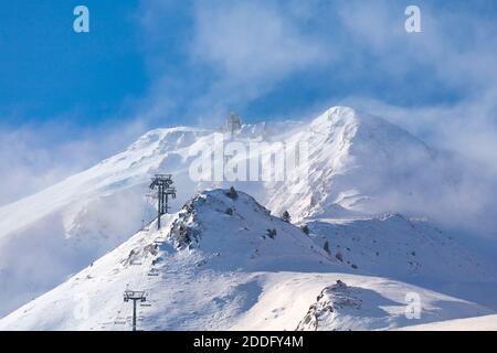 Leerer Skilift auf dem Weg zur Spitze des schneebedeckten Berges, der in der Wolke verloren ist. Stockfoto