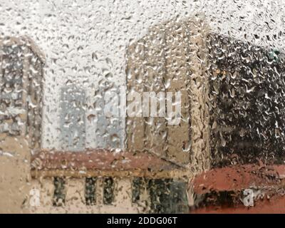 Hintergrund mit Regentropfen auf Fensterscheibe gegen Gebäude in Ein regnerischer Tag Stockfoto