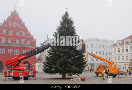 Greifswald, Deutschland. November 2020. Greifswald, Deutschland. November 2020. Ein Angestellter der Stadt Greifswald, der als Weihnachtsmann verkleidet ist, schmückt zusammen mit der Feuerwehr den Weihnachtsbaum auf dem historischen Marktplatz. Traditionell kommen mehrere hundert Kinder aus Kindertagesstätten, mit Eltern oder Großeltern, um den Baum zu schmücken und hausgemachte Weihnachtsdekorationen an den Zweigen zu hängen. In den Vorjahren durften die Kinder auf der Drehleiter der Feuerwehr reiten. Quelle: dpa picture Alliance/Alamy Live News Stockfoto