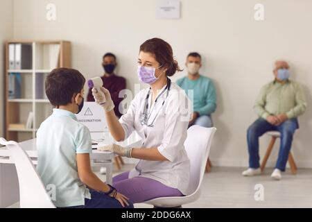Medizinische Krankenschwester, die die Temperatur des kleinen Jungen mit einem modernen berührungslosen Thermometer misst Stockfoto