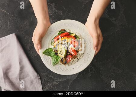 Frau mit Reissalat auf dunklem Hintergrund Stockfoto