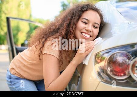 Afroamerikanische Frau, die ihr Auto im Freien putzt Stockfoto