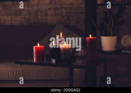 Schöne Duftkerzen auf dem Tisch im dunklen Raum Stockfoto