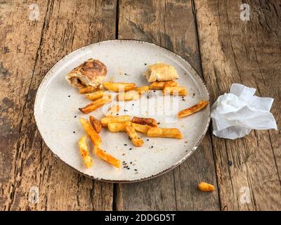 Reste von Burgern und pommes auf dem Teller Holztisch Stockfoto