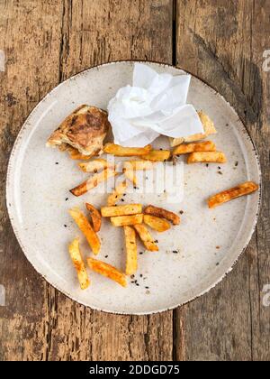 Reste von Burgern und pommes auf dem Teller Holztisch Stockfoto