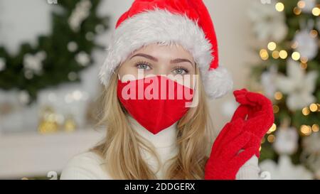 Porträt einer schönen Frau in weihnachtsmütze. Die Frau trägt die Schutzmaske des Virus Stockfoto