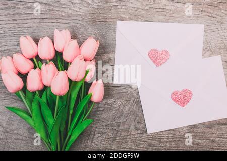 Bouquet von rosa Tulpen und weißen leeren Umschlägen, auf Holzgrund. Valentinstag Stockfoto