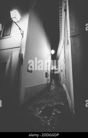 Eine vertikale Graustufenaufnahme der Straßen Portugals eingefangen Während der Nacht Stockfoto