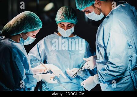 Gruppe von fokussierten professionellen Chirurgen mit chirurgischen Werkzeugen und Faden Beenden des Betriebs des Patienten im OP Stockfoto