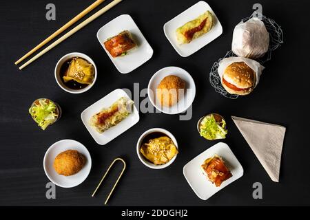 Blick von oben auf verschiedene leckere Fusion Food auf schwarz angeordnet Tisch im Restaurant Stockfoto