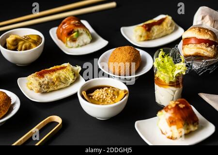 Blick von oben auf verschiedene leckere Fusion Food auf schwarz angeordnet Tisch im Restaurant Stockfoto