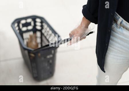 Von oben der Ernte unkenntlich weibliche Käufer in Zellophan Handschuhe Einkaufskorb beim Einkauf im Supermarkt während des Coronavirus tragen p Stockfoto