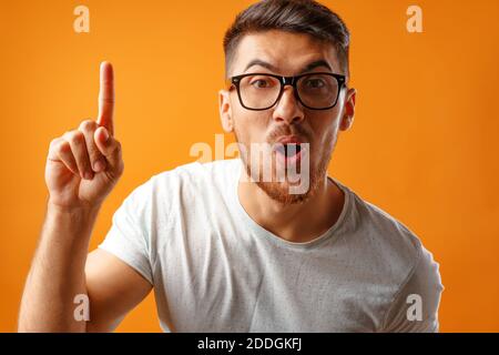 Nerdy überrascht Mann in Brille, die eine Idee setzen hat Mit dem Finger nach oben Stockfoto