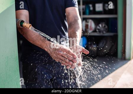 Crop anonymen männlichen Arbeiter waschen Hände unter fließendem Wasser Nach Abschluss der Arbeiten in der Reparaturwerkstatt Stockfoto