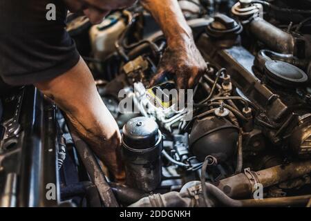 Von oben Ernte männlichen Mechaniker Beleuchtung Motor mit Taschenlampe und Fahrzeugmotor während der Arbeit in der Garage prüfen Stockfoto