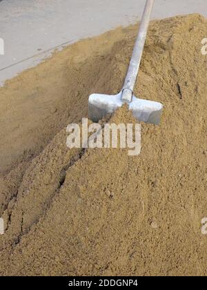 In einem Sandhaufen ragt eine Schaufel hervor. Stockfoto