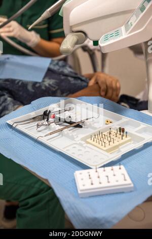 Verschiedene zahnärztliche Werkzeuge auf dem Tisch in der Klinik auf verschwommen platziert Hintergrund von nicht erkennbaren Zahnärzten und Patienten Stockfoto
