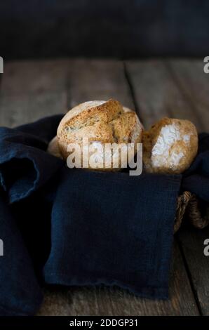 Frisch gebackene Brötchen auf Holztisch mit Serviette angeordnet In der Küche Stockfoto