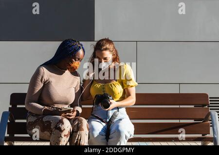 Begeisterte diverse Freundinnen, die Musik hören und durchschauen Fotos auf Fotokamera auf der Straße gemacht Stockfoto