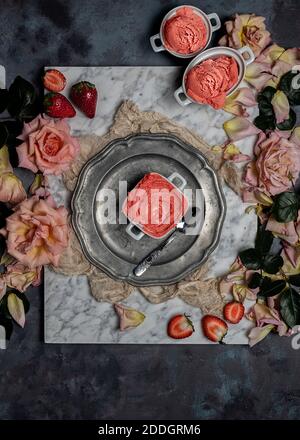 Draufsicht Zusammensetzung mit köstlichen hausgemachten Erdbeer Sorbet serviert auf Tisch mit frischen Beeren und Rosenblüten Stockfoto