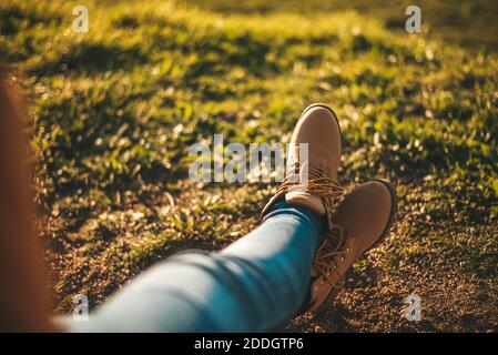 Detail von einigen Füßen mit Stiefeln, die sich gegen Gras entspannen Stockfoto