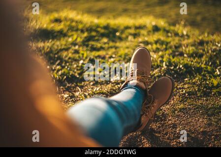 Detail von einigen Füßen mit Stiefeln, die sich gegen Gras entspannen Stockfoto