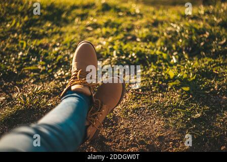 Detail von einigen Füßen mit Stiefeln, die sich gegen Gras entspannen Stockfoto